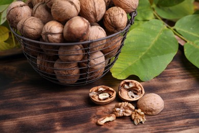 Photo of Walnuts and fresh green leaves on wooden table