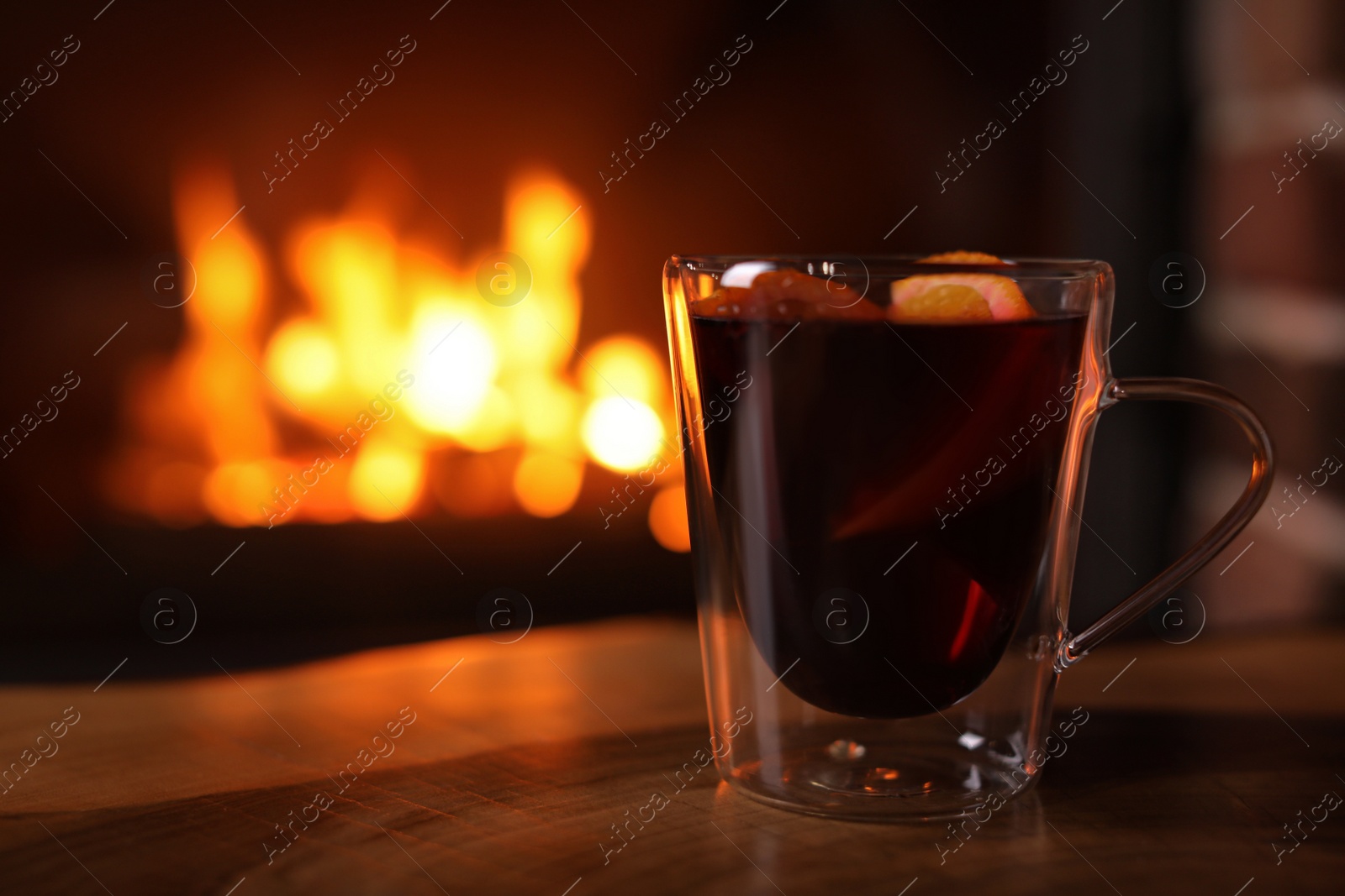 Photo of Tasty mulled wine, plaid and blurred fireplace on background