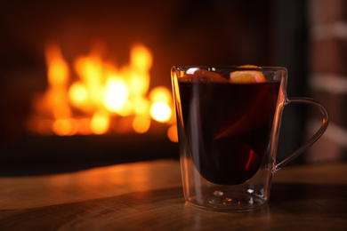 Photo of Tasty mulled wine, plaid and blurred fireplace on background
