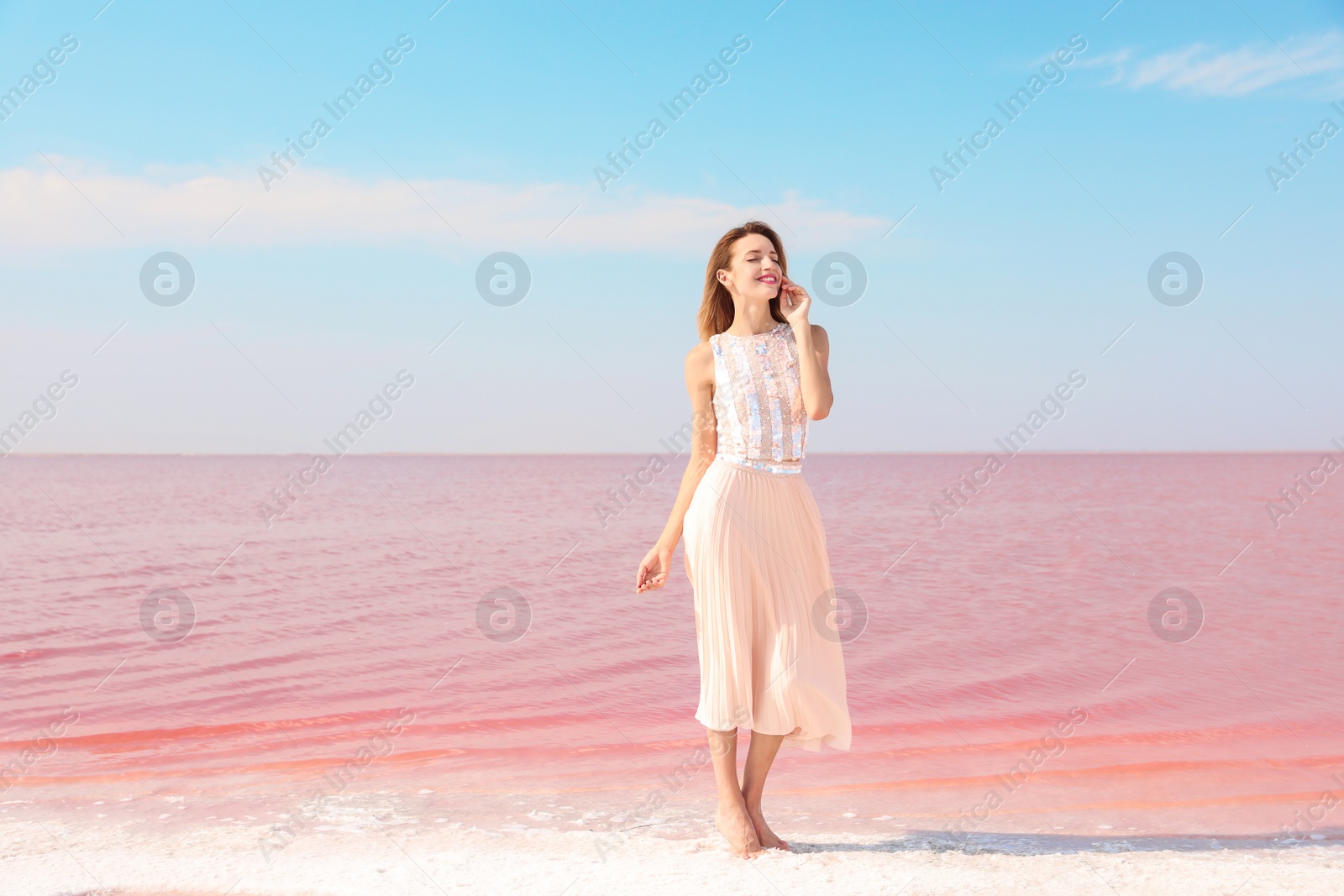 Photo of Beautiful woman posing near pink lake on sunny day