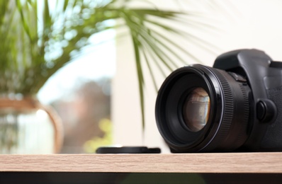 Photo of Professional camera on table against blurred background, space for text. Photographer's equipment