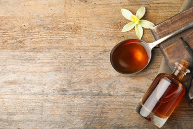 Photo of Flat lay composition with vanilla extract on wooden table. Space for text