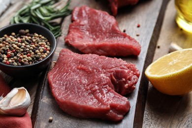 Photo of Fresh raw meat steaks and spices on wooden table, closeup