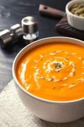 Delicious pumpkin cream soup in bowl on table