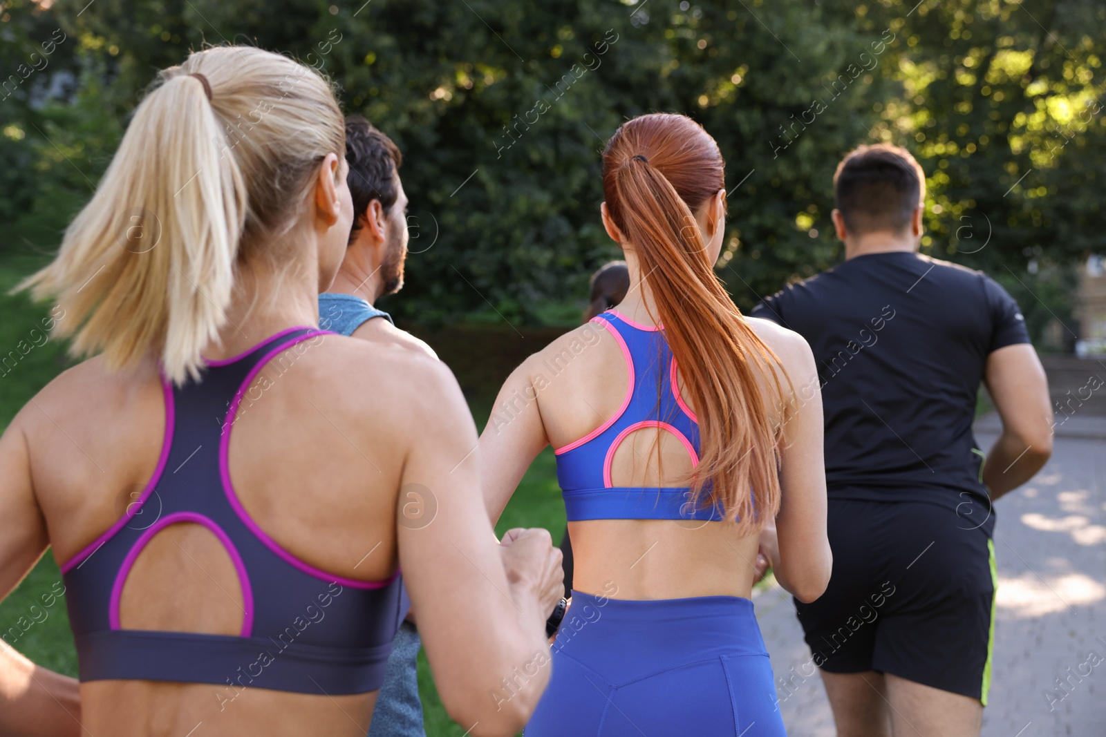 Photo of Group of people running in park, back view