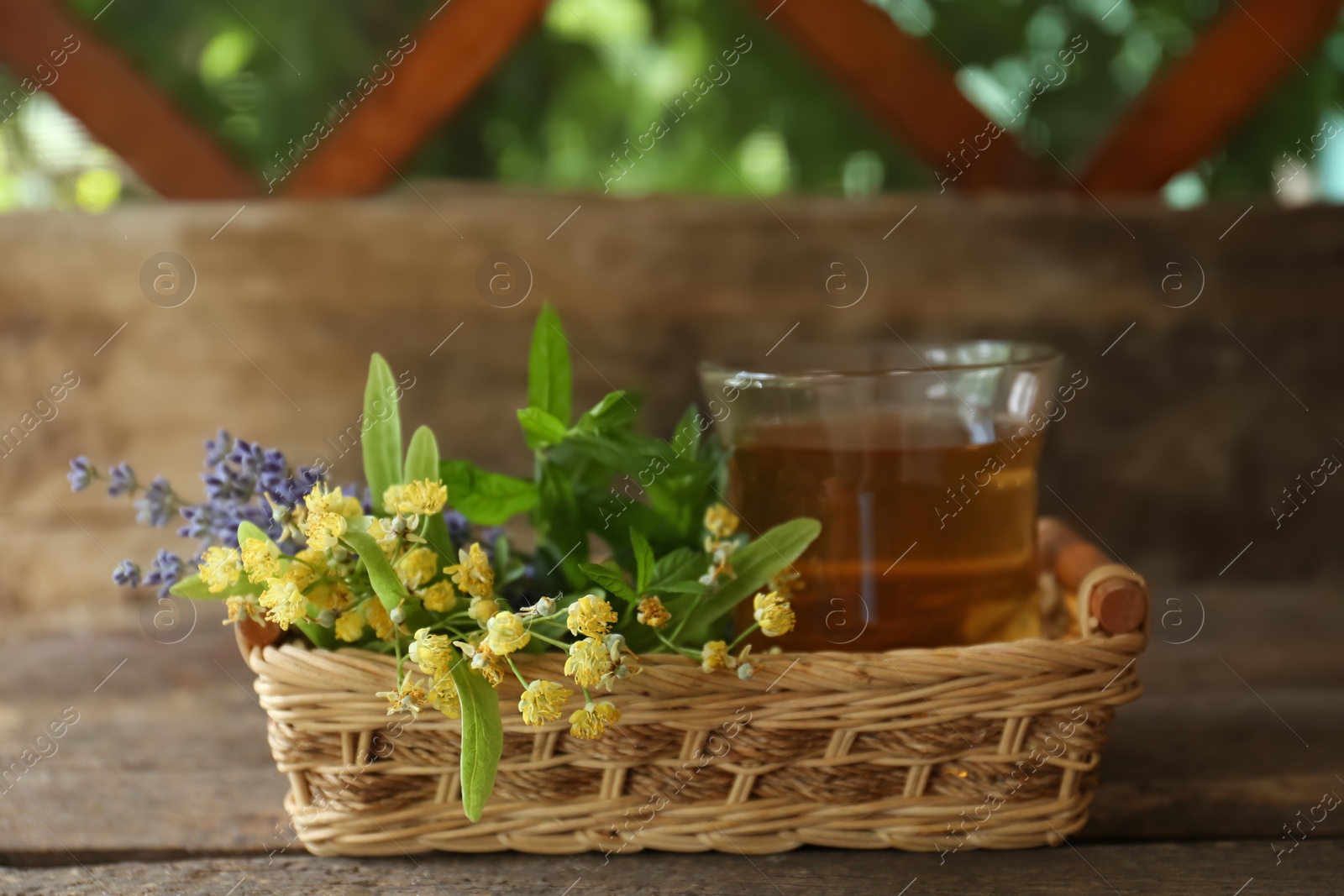 Photo of Tasty herbal tea, fresh lavender flowers and linden branches on wooden table