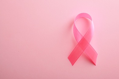 Pink ribbon on color background, top view with space for text. Breast cancer awareness concept