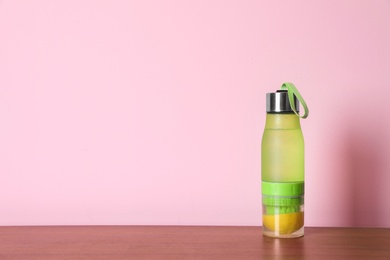 Photo of Sport bottle with lemon water on color background. Space for text