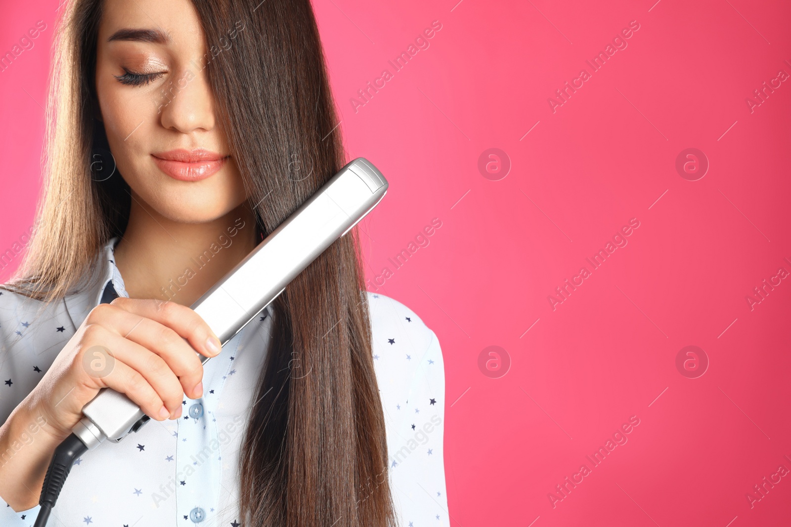 Photo of Happy woman using hair iron on color background. Space for text