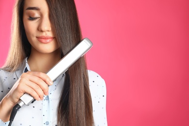 Happy woman using hair iron on color background. Space for text