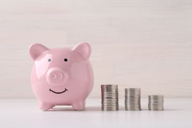 Financial savings. Piggy bank and stacked coins on white wooden table