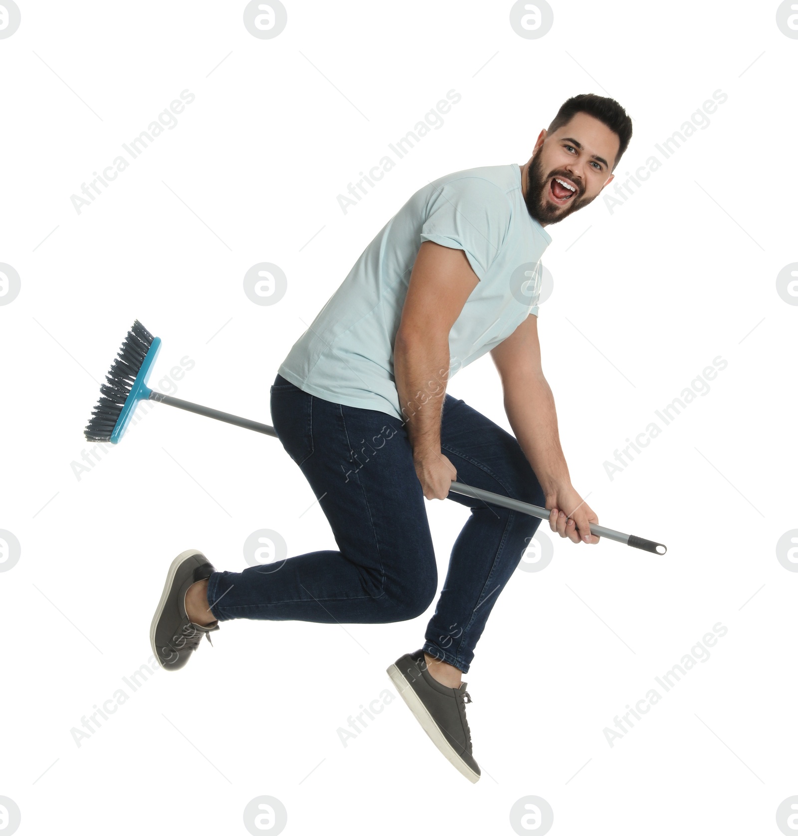 Photo of Young man with broom jumping on white background