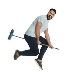 Photo of Young man with broom jumping on white background