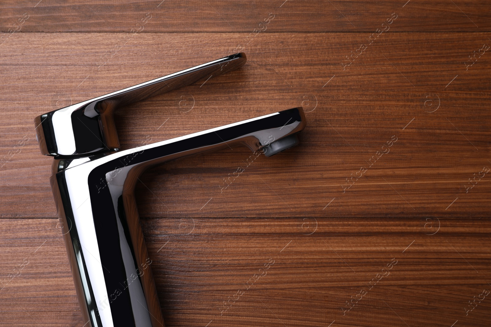 Photo of Single handle water tap on wooden table, top view. Space for text