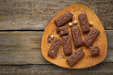 Photo of Delicious chocolate candy bars with nuts on wooden table, top view. Space for text