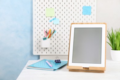Photo of Modern tablet and stationery on white wooden desk. Space for text