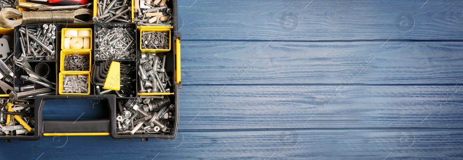 Image of Box with different furniture fittings and tools on blue wooden table, top view. Banner design with space for text