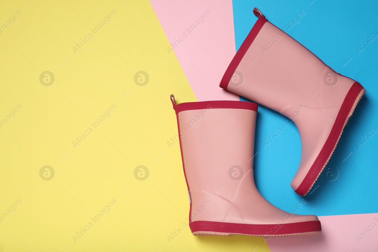 Photo of Pink rubber boots on color background, flat lay. Space for text