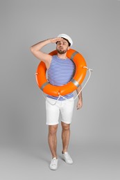 Photo of Sailor with ring buoy on light grey background