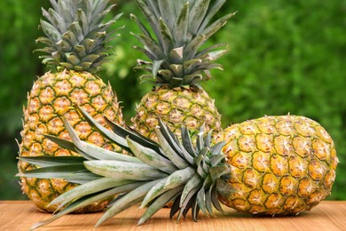 Delicious ripe pineapples on wooden table outdoors