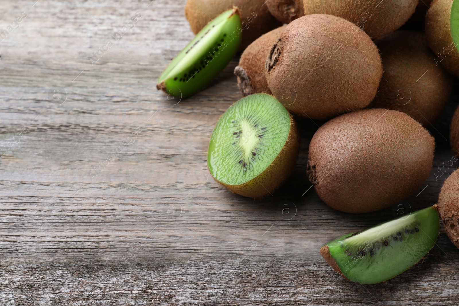 Photo of Pile of fresh ripe kiwis on wooden table, closeup. Space for text