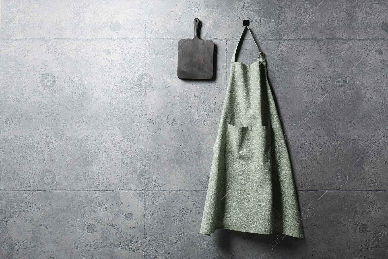 Photo of Clean kitchen apron with pattern and board on grey tiled wall. Space for text