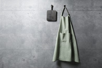 Photo of Clean kitchen apron with pattern and board on grey tiled wall. Space for text