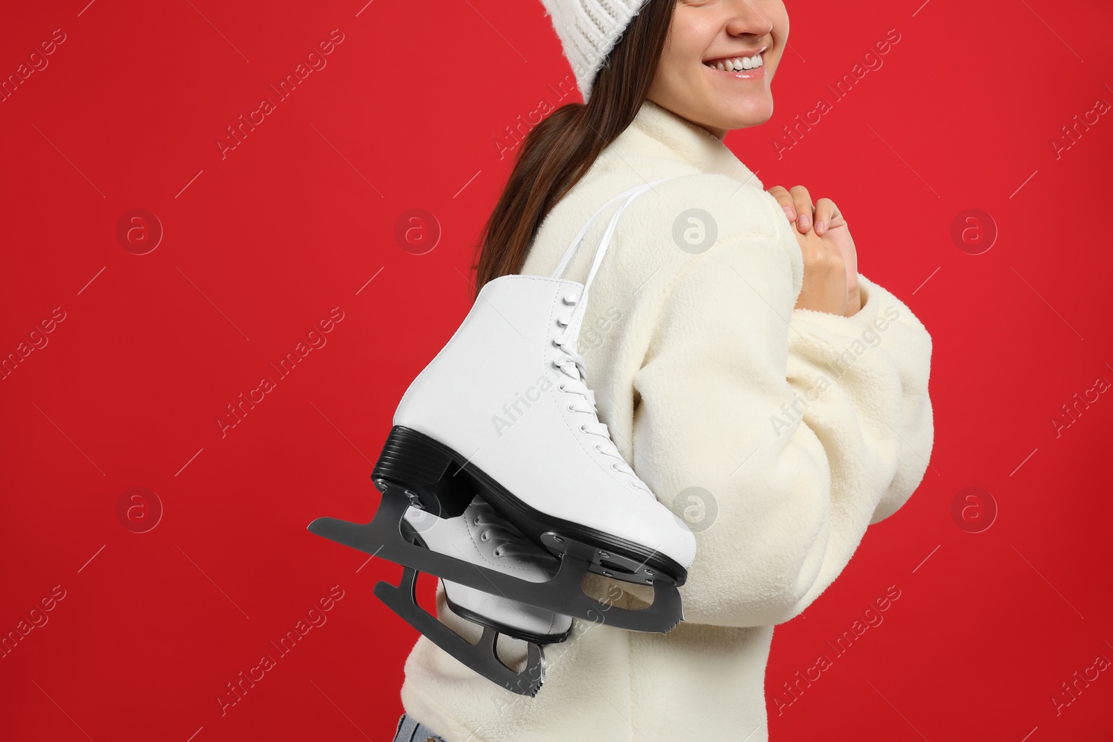 Photo of Happy woman with ice skates on red background, closeup