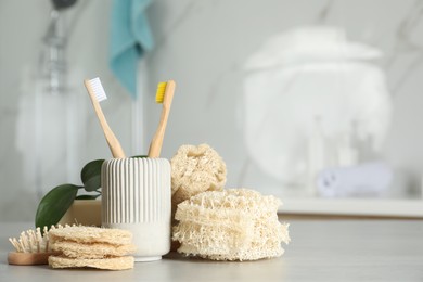 Photo of Composition with natural loofah sponges on table in bathroom. Space for text