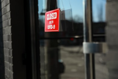 Red sign with text Closed Due To Covid-19 hanging on glass door. Coronavirus quarantine