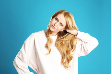 Portrait of beautiful young woman with dyed long hair on blue background