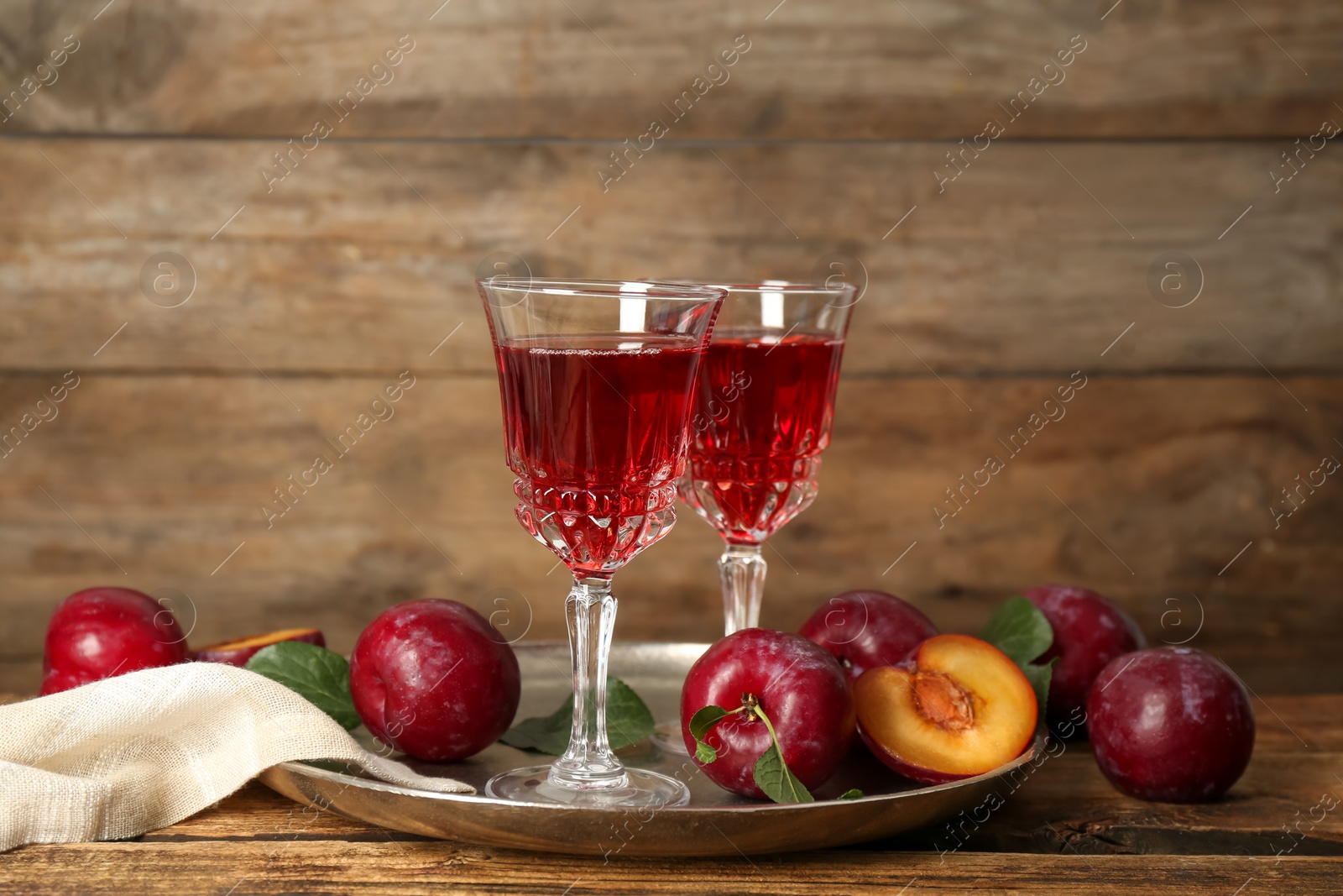 Photo of Delicious plum liquor and ripe fruits on wooden table. Homemade strong alcoholic beverage