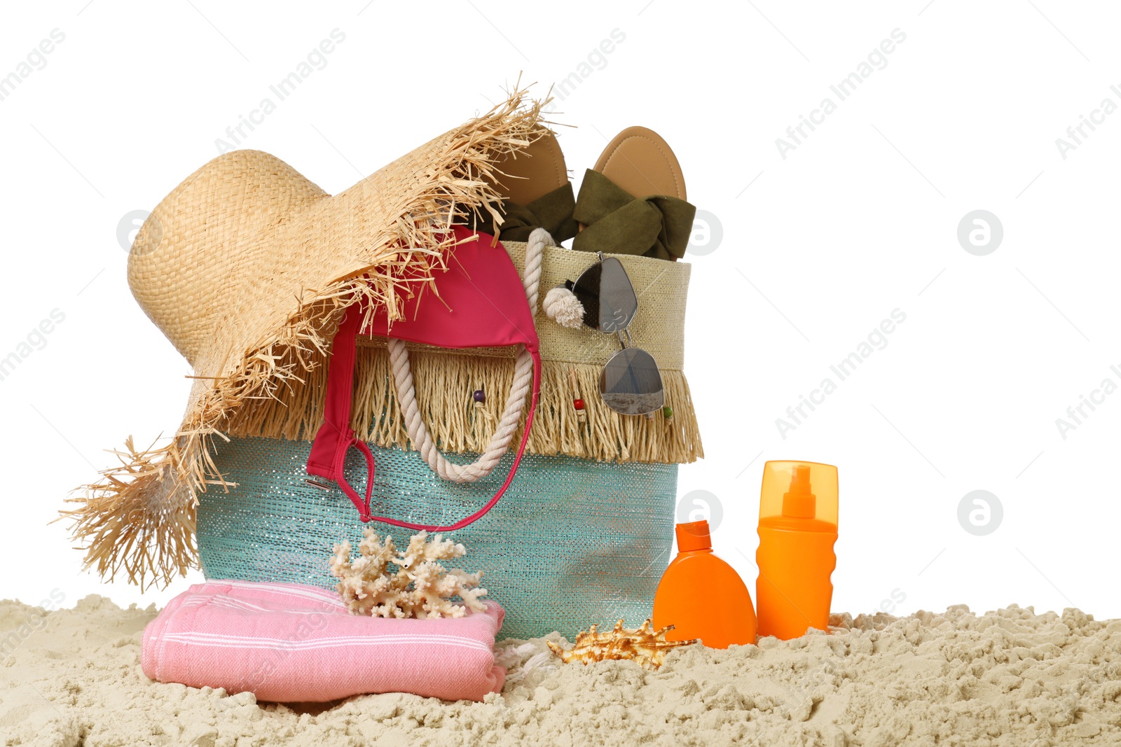 Photo of Stylish bag with beach accessories on sand against white background