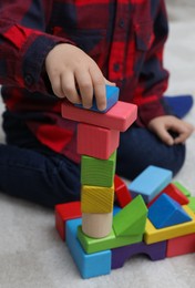 Photo of Little child playing with building blocks on carpet, closeup