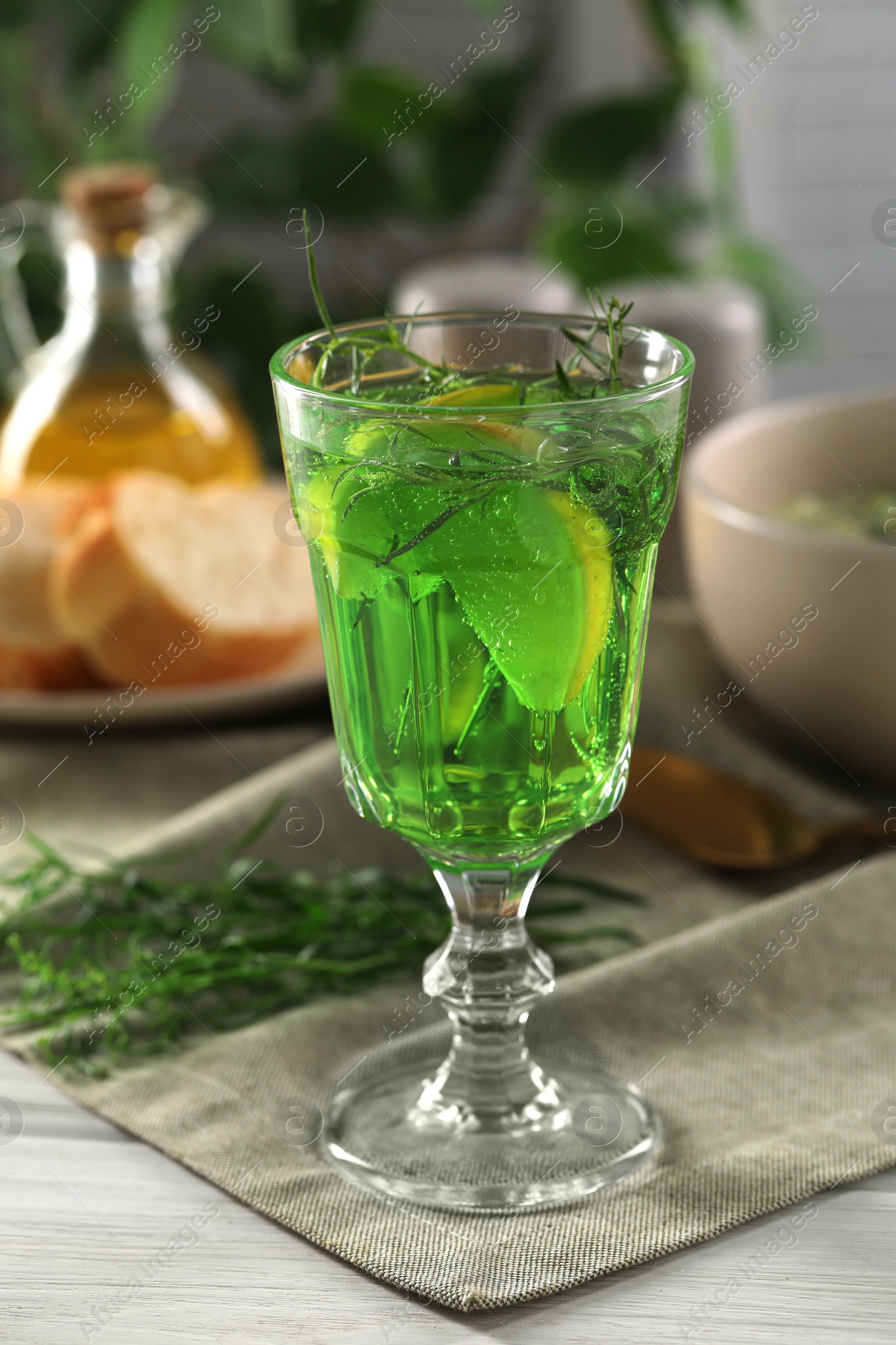 Photo of Delicious drink with tarragon in glass on white wooden table