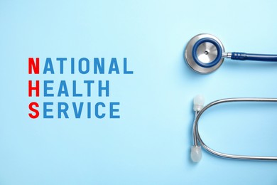 National health service (NHS). Stethoscope and text on light blue background, top view