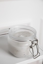 Photo of Jar of salt scrub on white table, closeup