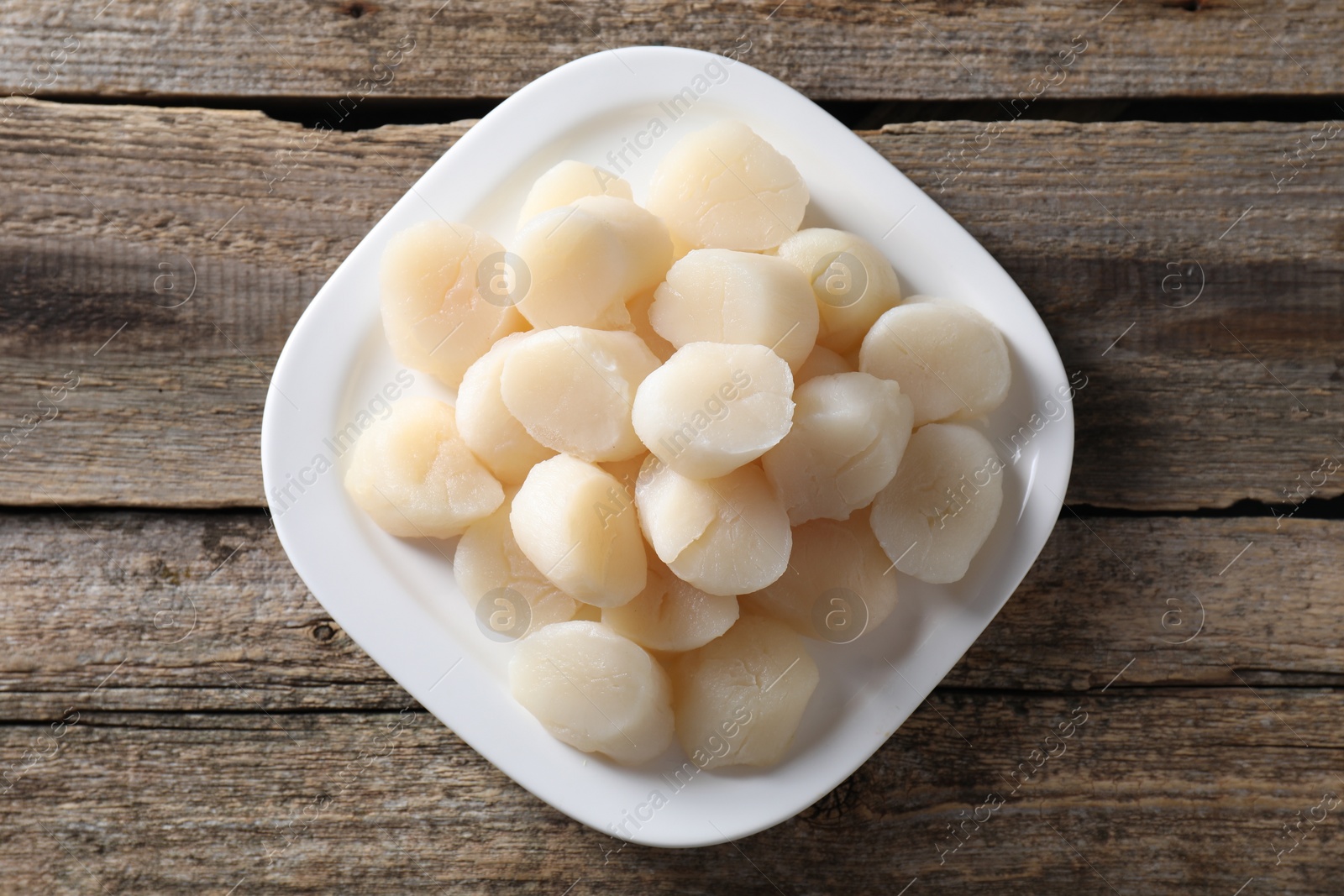 Photo of Fresh raw scallops on wooden table, top view