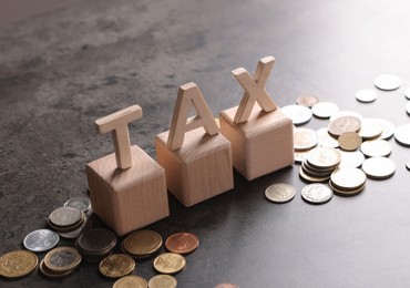 Word Tax, wooden letters and coins on grey table, space for text