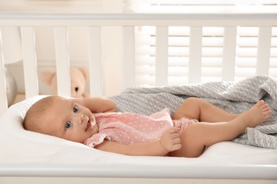 Photo of Cute little baby lying in soft crib