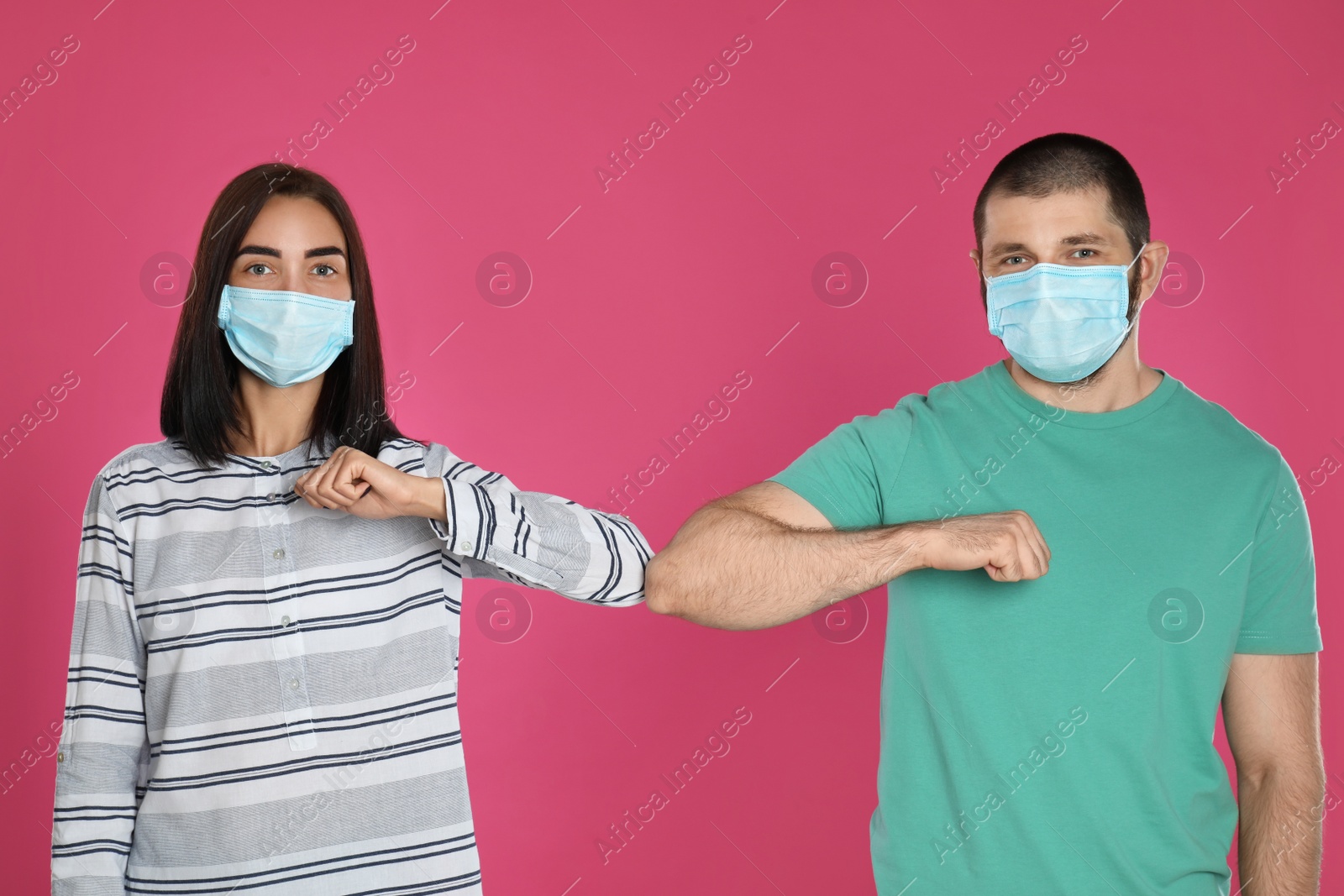 Photo of Man and woman bumping elbows to say hello on pink background. Keeping social distance during coronavirus pandemic