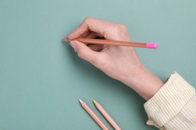 Photo of Woman drawing on color paper with pastel pencil, top view