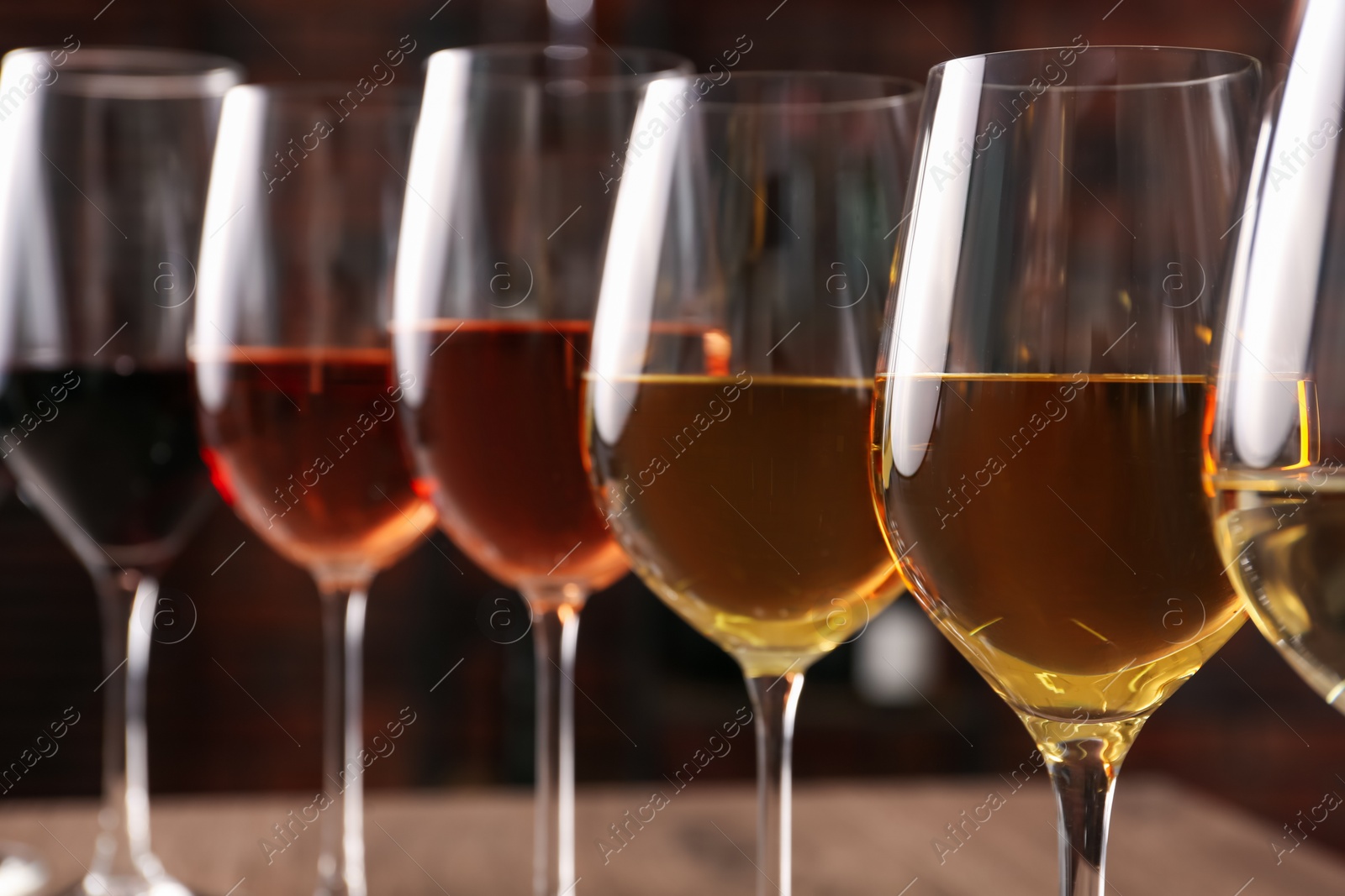 Photo of Different tasty wines in glasses against blurred background