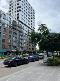 Photo of WARSAW, POLAND - JULY 11, 2022: Exterior of modern residential building with balconies and cars parked nearby
