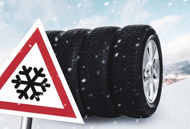 Set of wheels with winter tires on snow and road sign outdoors