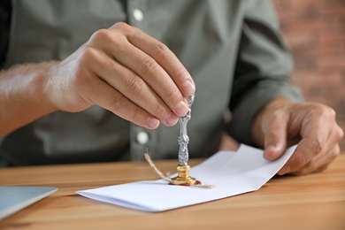 Photo of Male notary stamping document at table, closeup