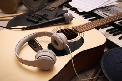 Photo of Acoustic guitar, headphones and microphone on wooden background, closeup