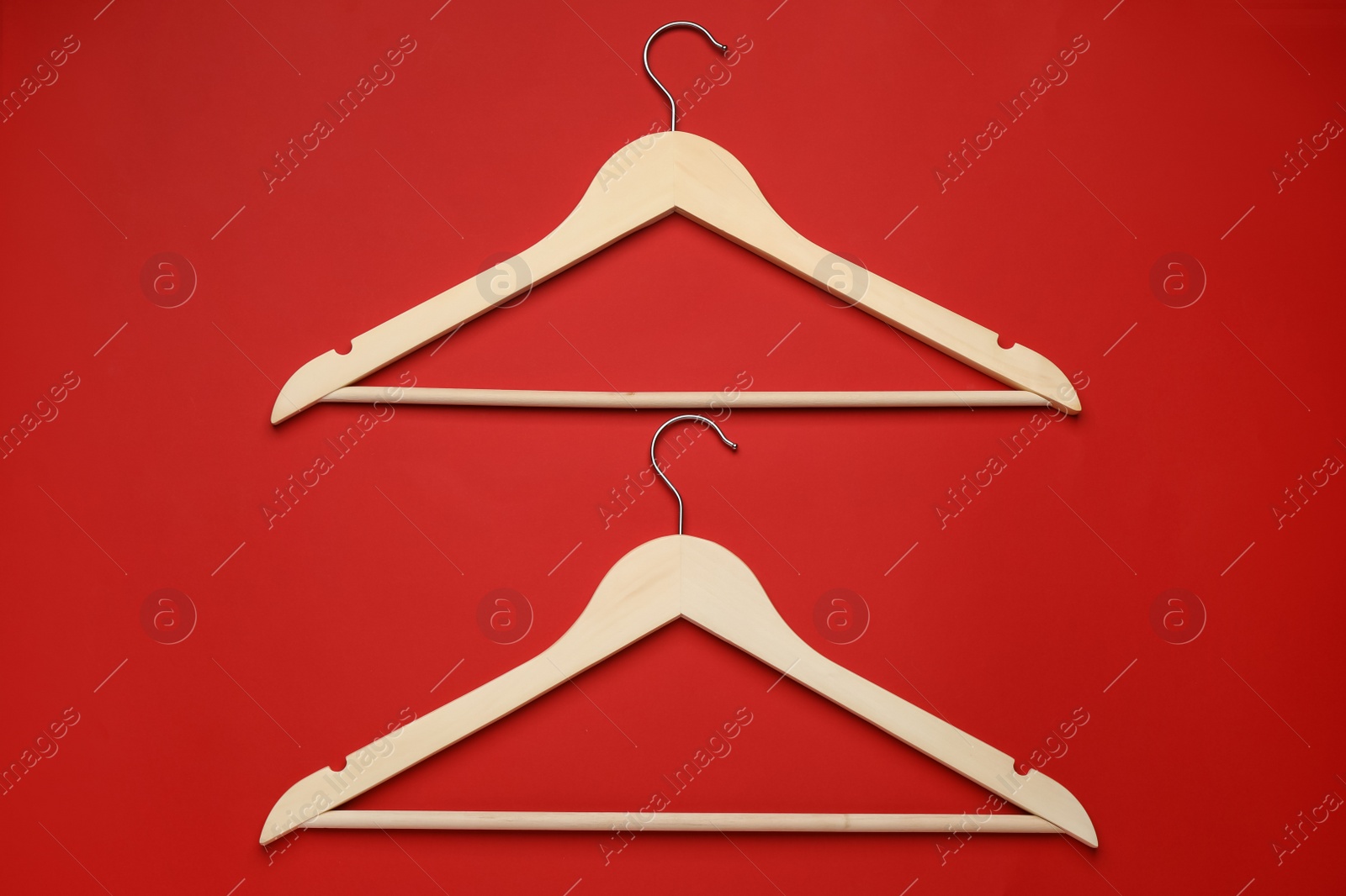 Photo of Empty clothes hangers on red background, flat lay