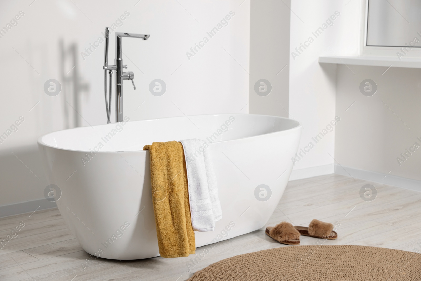Photo of Stylish bathroom interior with ceramic tub and terry towels