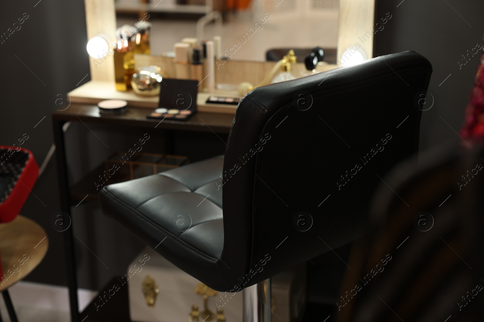 Photo of Makeup room. Chair near dressing table with different beauty products indoors